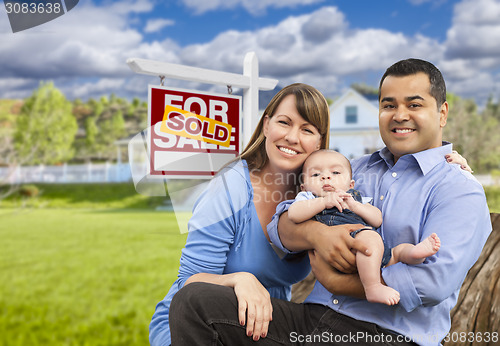 Image of Young Family in Front of Sold Real Estate Sign and House
