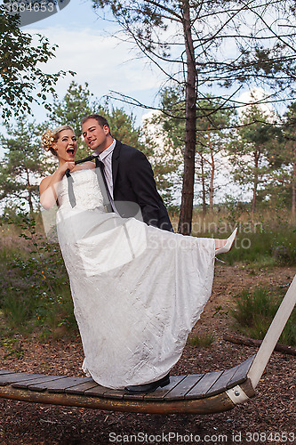 Image of Young married couple is frivolous on a large swing.