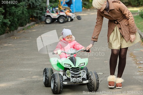 Image of Little girl riding toy car in park