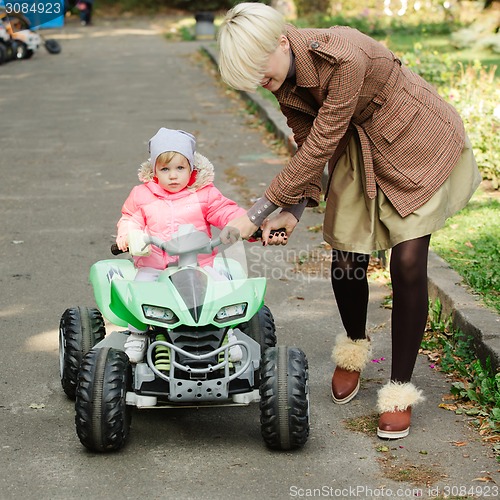 Image of Little girl riding toy car in park