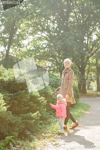 Image of Beautiful Mother And Baby outdoors. Nature. Beauty Mum and her Child playing in Park together. Outdoor Portrait of happy family. Joy.