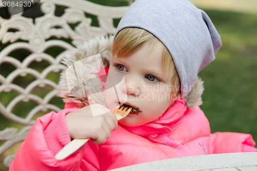 Image of Child eating waffles with chocolate in park
