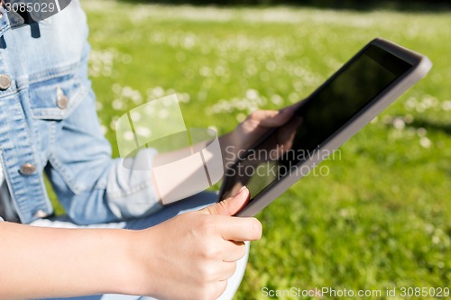 Image of close up of girl with tablet pc sitting on grass