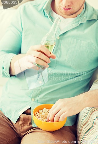 Image of close up of man with popcorn and beer at home
