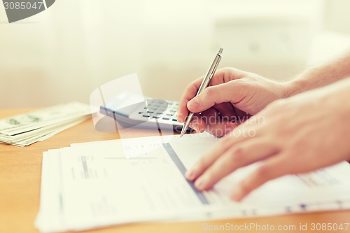 Image of close up of man counting money and making notes