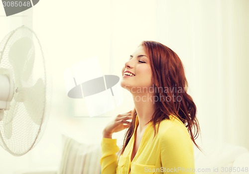 Image of smiling redhead teenage girl with big fan at home