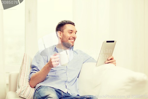 Image of smiling man working with tablet pc at home