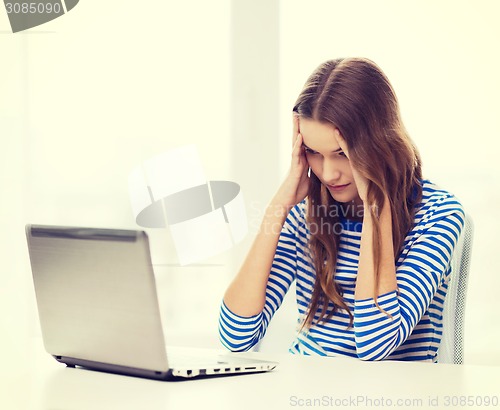 Image of upset teenage gitl with laptop computer at home