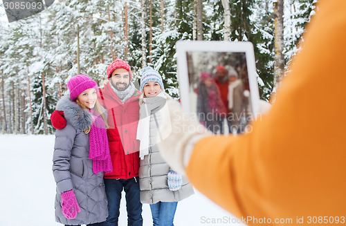 Image of smiling friends with tablet pc in winter forest