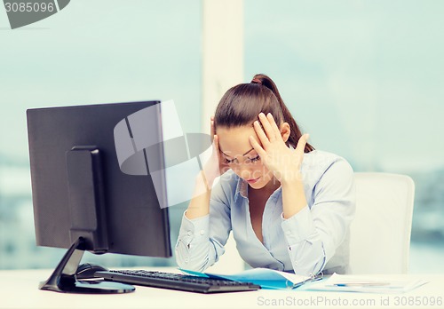 Image of stressed woman with computer and documents