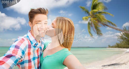 Image of happy couple taking selfie on tropical beach