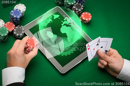 Image of casino poker player with cards, tablet and chips