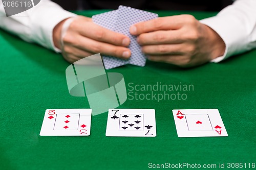 Image of poker player holding playing cards at casino table