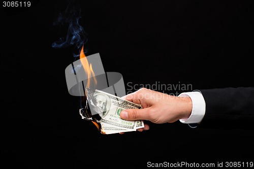 Image of close up of male hand holding burning dollar money