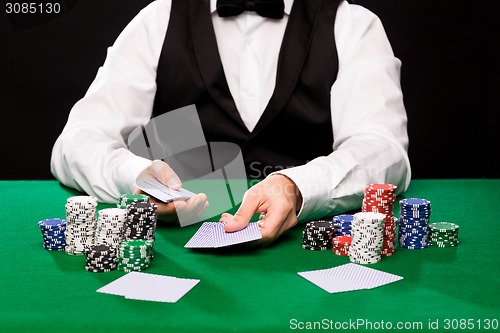 Image of holdem dealer with playing cards and casino chips