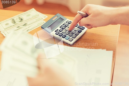 Image of close up of man counting money and making notes