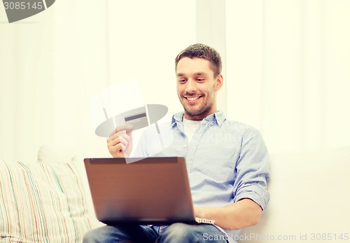 Image of smiling man working with laptop and credit card