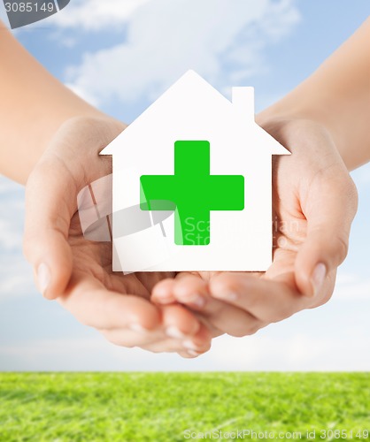 Image of hands holding paper house with green cross