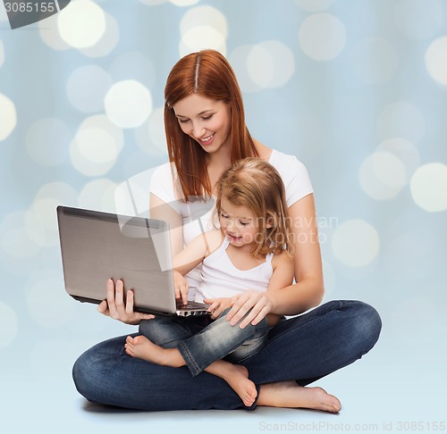 Image of happy mother with adorable little girl and laptop