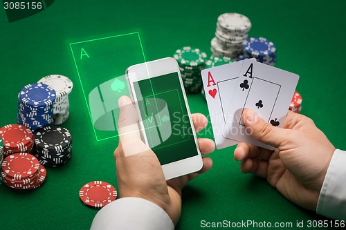 Image of casino player with cards, smartphone and chips