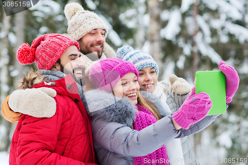 Image of smiling friends with tablet pc in winter forest