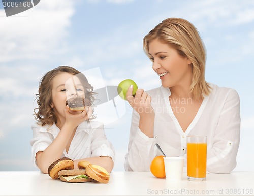 Image of happy mother and daughter eating breakfast