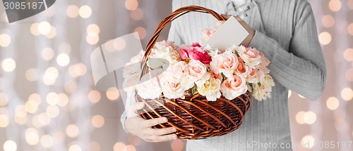 Image of man holding basket full of flowers and postcard