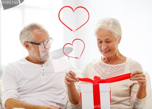 Image of happy senior couple with gift box at home