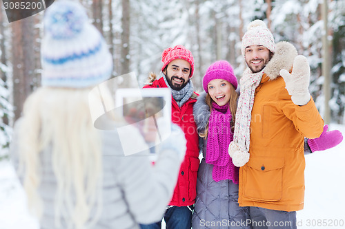 Image of smiling friends with tablet pc in winter forest