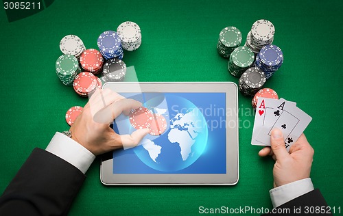 Image of casino poker player with cards, tablet and chips