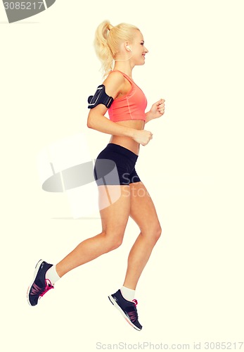 Image of sporty woman running with smartphone and earphones