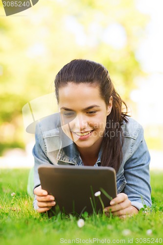 Image of smiling young girl tablet pc lying on grass