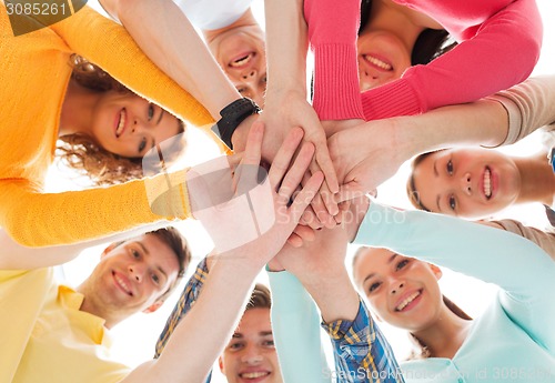 Image of smiling teenagers with hands on top of each other