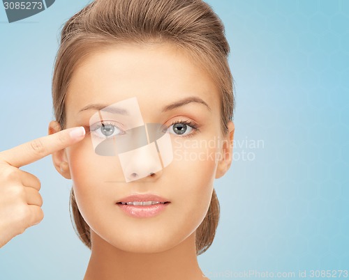 Image of beautiful young woman pointing finger to her eye