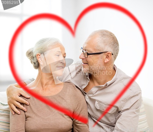 Image of happy senior couple hugging on sofa at home