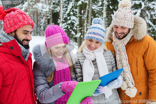 Image of smiling friends with tablet pc in winter forest
