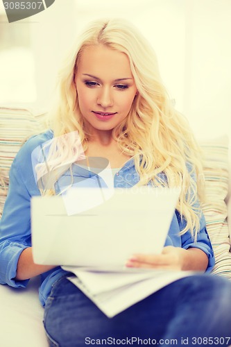 Image of smiling young woman with papers at home