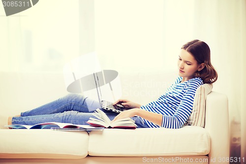 Image of smiling teenage girl with laptop computer at home