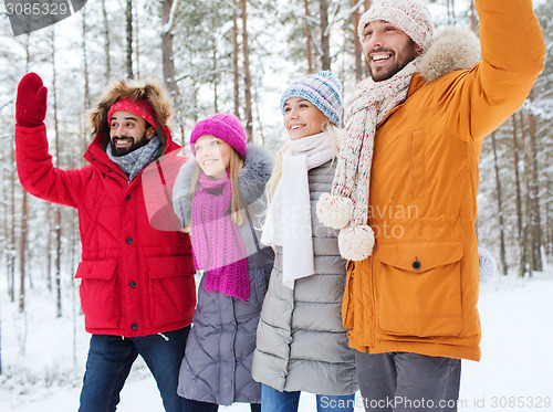 Image of group of friends waving hands in winter forest