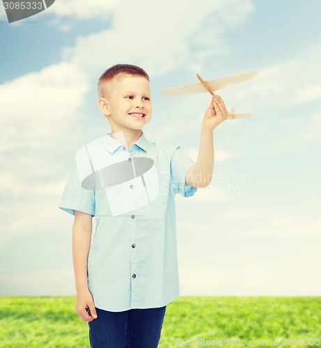 Image of smiling little boy holding a wooden airplane model