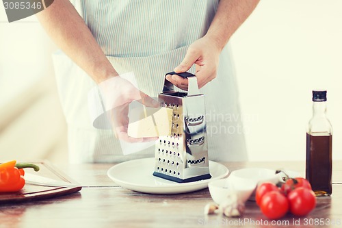 Image of close up of male hands grating cheese