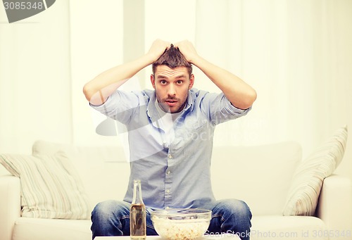 Image of sad man watching sports at home