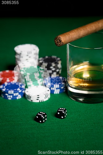 Image of close up of chips, dice, whisky and cigar on table