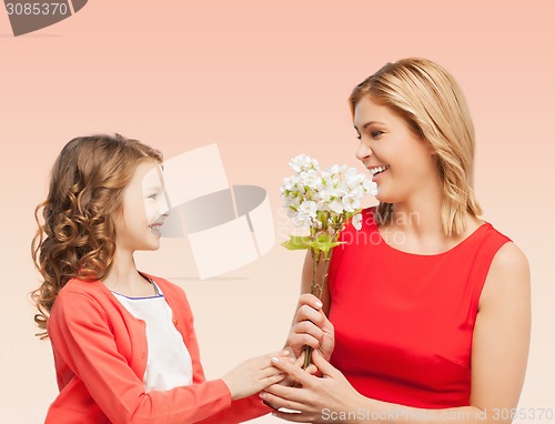 Image of happy little daughter giving flowers to her mother