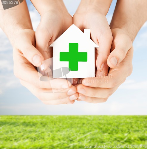 Image of hands holding paper house with green cross