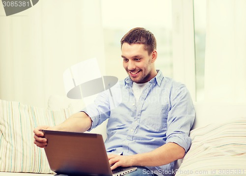 Image of smiling man working with laptop at home