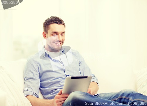 Image of smiling man working with tablet pc at home