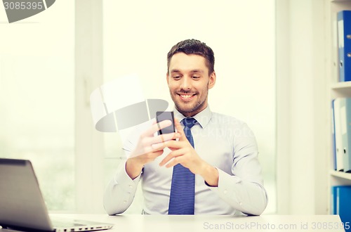 Image of businessman with laptop and smartphone at office