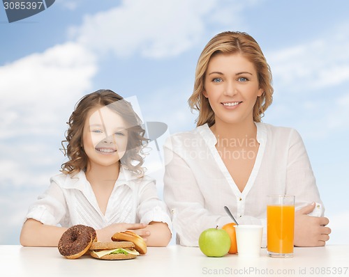 Image of happy mother and daughter eating breakfast