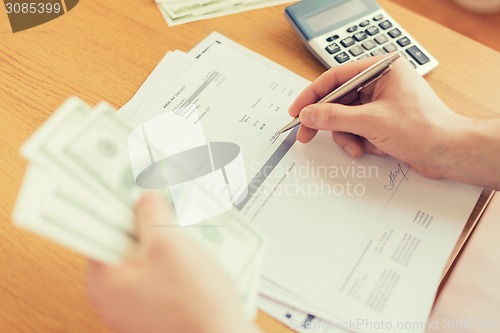 Image of close up of man counting money and making notes